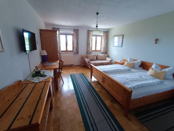 Helles Hotelzimmer mit zwei Betten, Fernseher und Holzmobiliar.