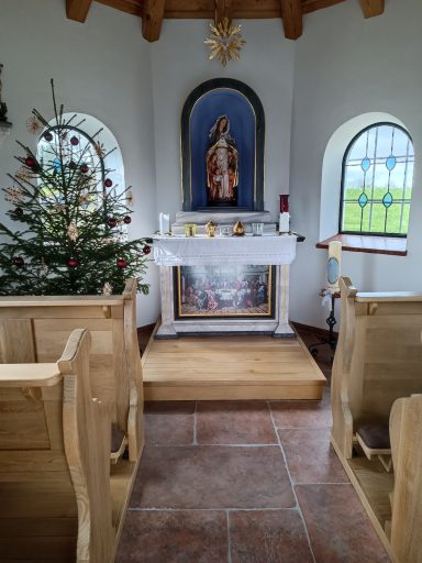 Innenansicht einer Kapelle mit Altar, Statue und Weihnachtsbaum.