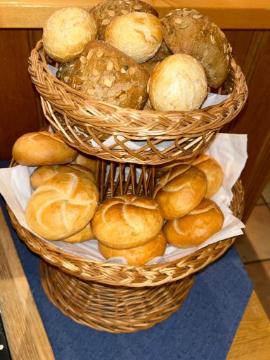 Korb mit verschiedenen Brötchen, darunter zarte, runde und krosse Sorten.