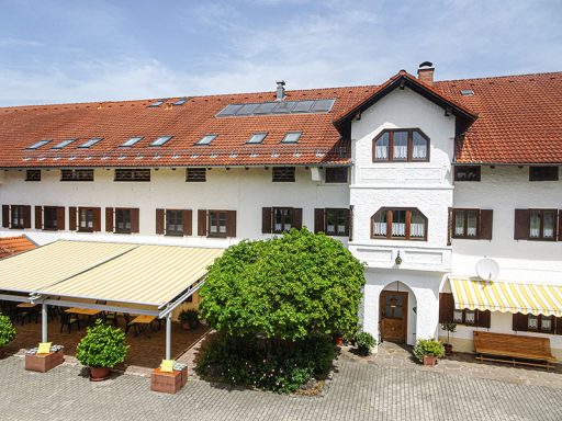 Traditionelles deutsches Gebäude mit rotem Satteldach und Gastgarten.