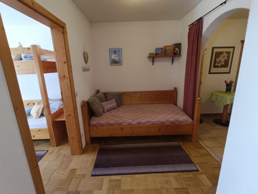 Gemütliches Zimmer mit einem Einzelbett, einem Hochbett und einem Bereich mit Tisch und Stühlen.